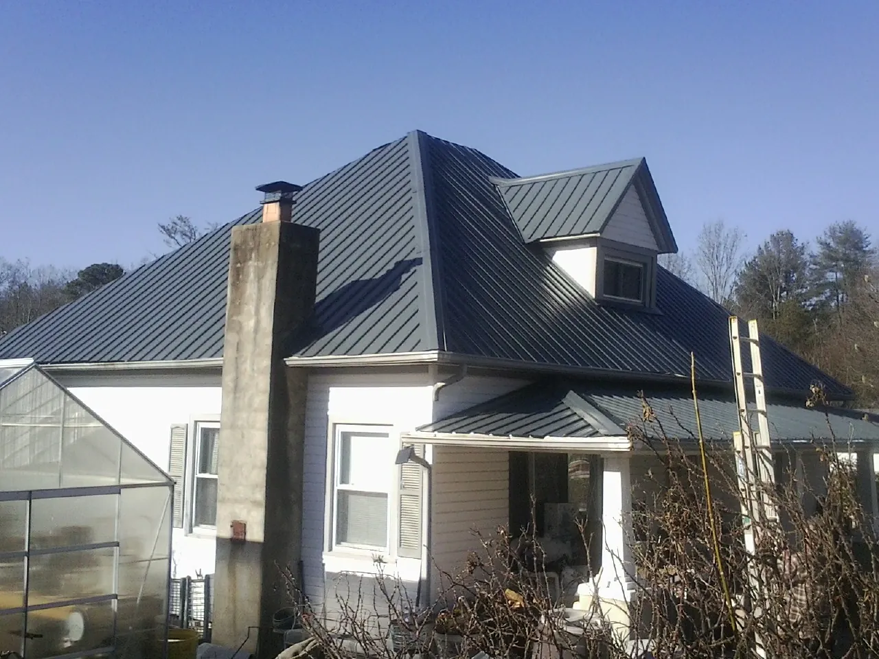 Dark blue standing seam metal roof on a white farmhouse with dormer — Slate & Tile Roof Repair by Roofing Brothers in Rancho Santa Fe