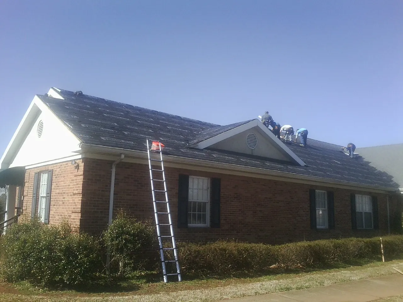 Crew tearing shingles off a brick ranch roof with a ladder set — Metal Roof Repair work by our crew in Rancho Santa Fe