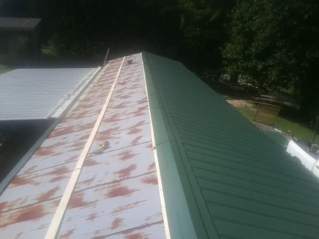 Old rusted panels beside newly installed green metal roofing — Wind Damage Roof Repair by Roofing Brothers in Rancho Santa Fe