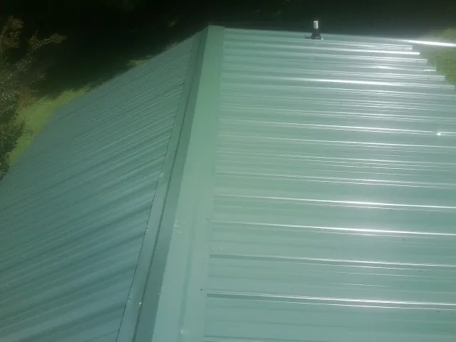 New green metal panels meeting at the ridge of a roof — Flat Roof Repair work by our crew in Rancho Santa Fe