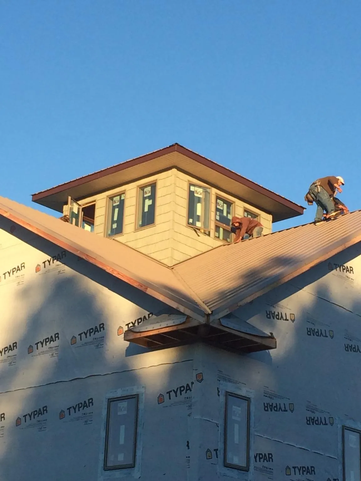 Roofers working around a rooftop cupola on a new metal roof at sunset — Roof Waterproofing in Rancho Santa Fe by Roofing Brothers